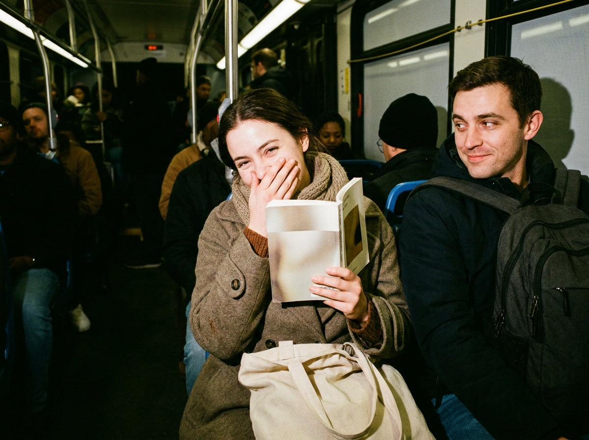 A reader laughing into her book on a late-night train